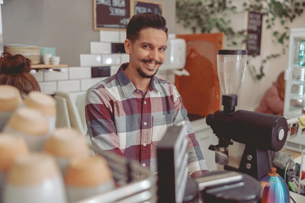 Knappe barista met snor glimlachend in de camera