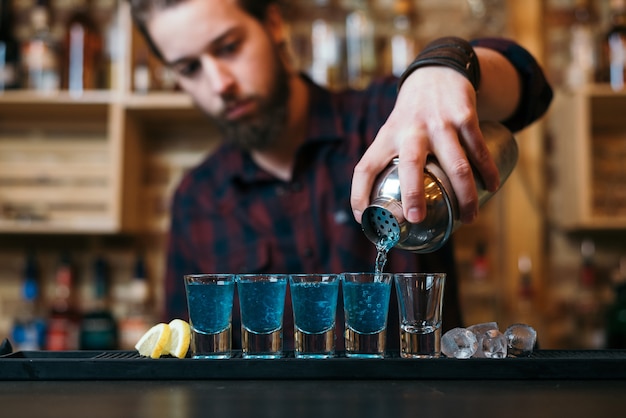 Knappe bebaarde barman maakt cocktails in nachtclub.