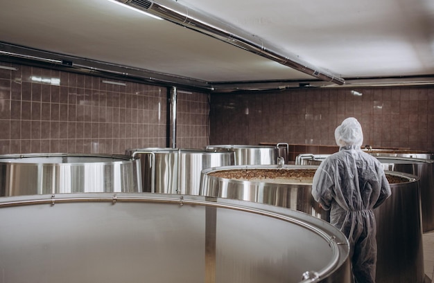 Knappe bebaarde brouwer die het fermentatieproces van bier controleert in zijn ambachtelijke bierfabriek