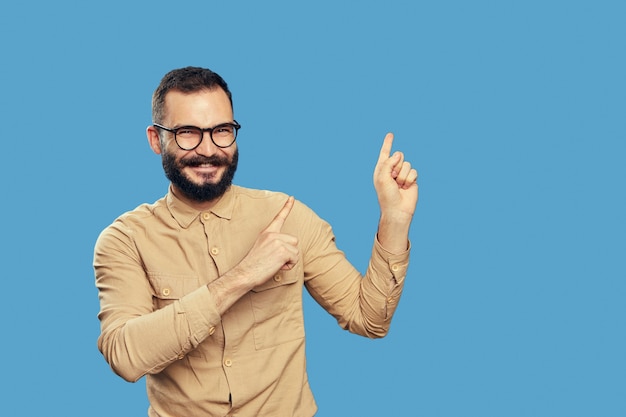 Knappe bebaarde hipster-man wijst met beide opzij op lege ruimte