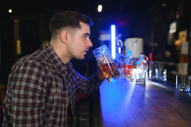 Knappe bebaarde man bier drinken aan de toog in pub