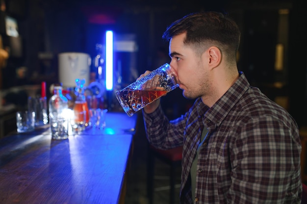 Knappe bebaarde man bier drinken aan de toog in pub