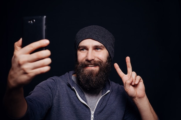 Knappe bebaarde man die selfie maakt met smartphone