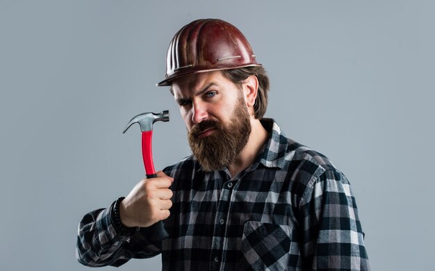 Knappe bebaarde man met baard en snor houdt hamergebouw vast