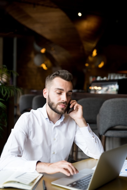 Knappe bebaarde man spreken via de telefoon