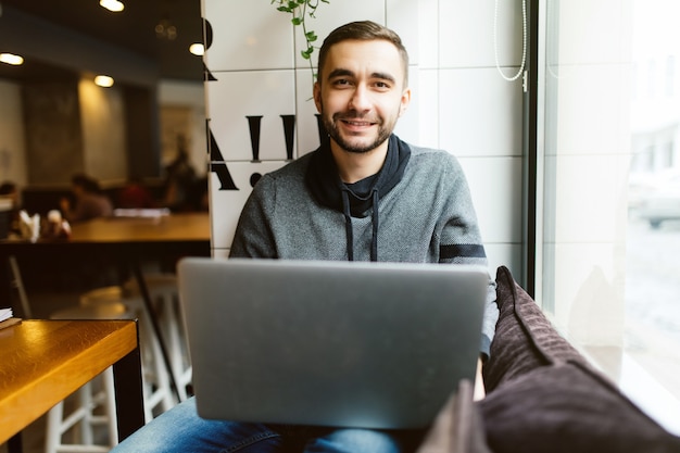 Knappe bebaarde man werkt op laptop zittend in café