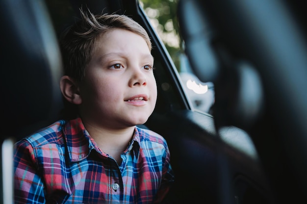 Knappe blanke jongen reizen met de auto zittend in kinderzitje Recreatie concept