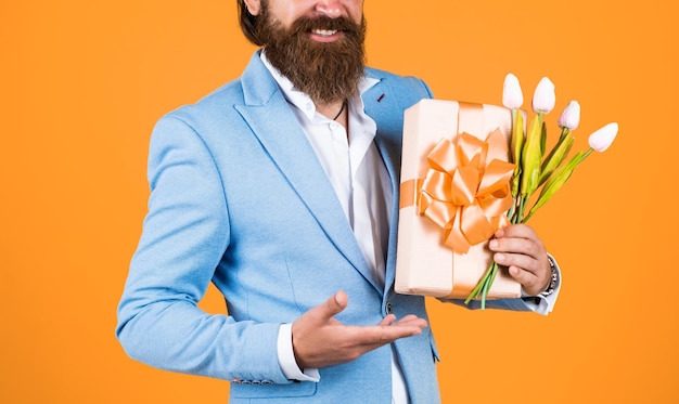 Knappe blanke zakenman met trendy kapsel in jasje met tulp bloemen verjaardag