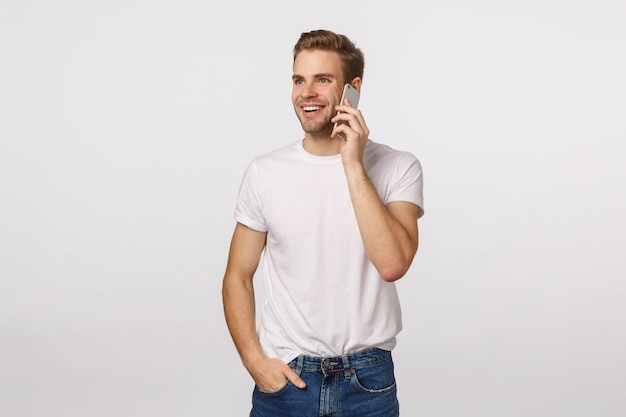 Knappe blonde man met blauwe ogen en wit t-shirt bellen