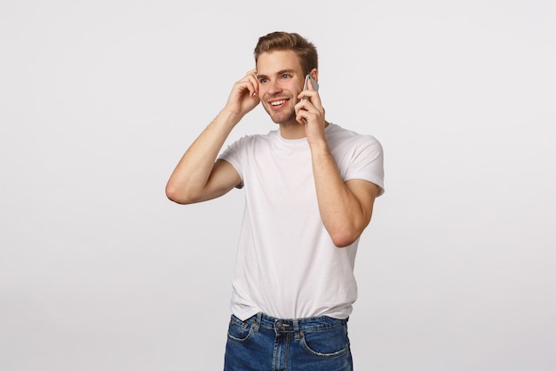 Knappe blonde man met blauwe ogen en wit T-shirt bellen