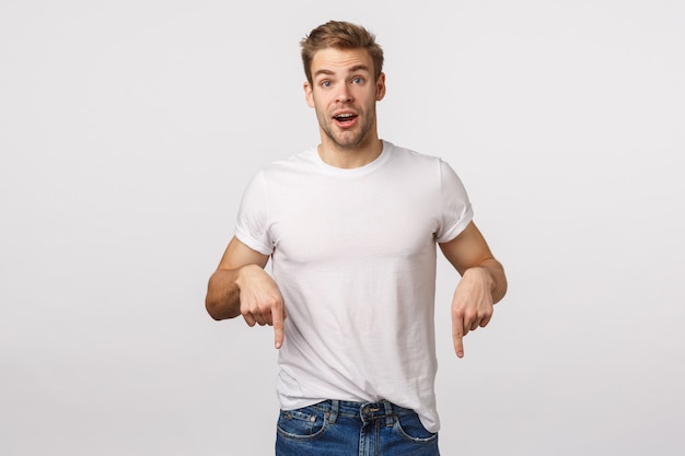 Knappe blonde man met blauwe ogen en wit t-shirt naar beneden gericht