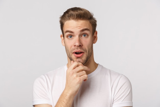 Knappe blonde man met blauwe ogen en witte t-shirt poseren