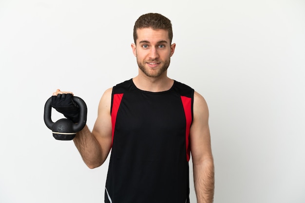 Knappe blonde man over geïsoleerde witte achtergrond die gewichtheffen maakt met kettlebell