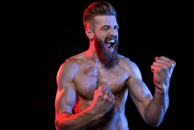 Knappe bodybuilder gebaren en schreeuwen geïsoleerd op zwart met dramatische verlichting