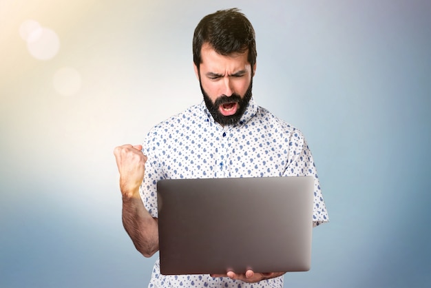 Knappe brunette man met baard met laptop