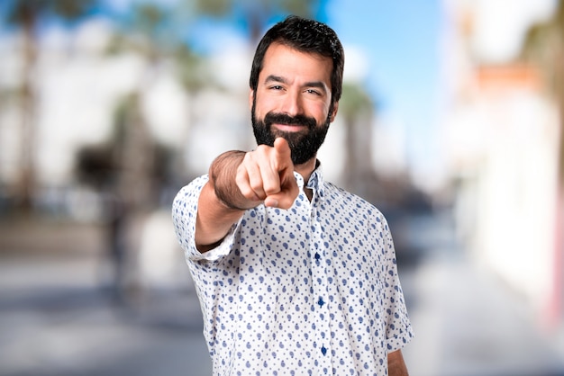 Foto knappe brunette man met baard wijst naar de voorkant