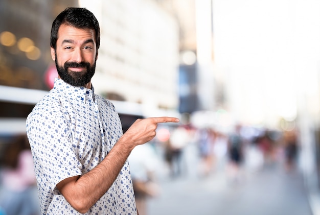 Knappe brunette man met baard wijst naar de zijkant