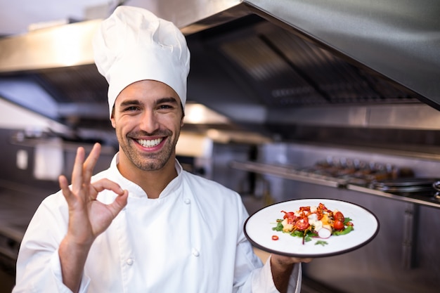 Knappe chef-kok die ok teken en maaltijd toont