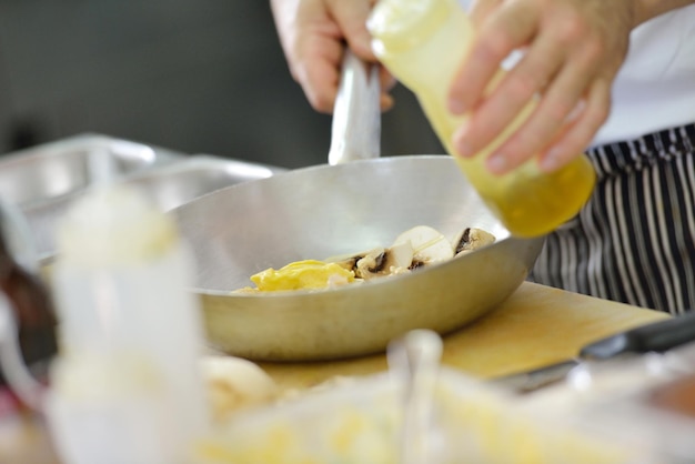 Knappe chef-kok gekleed in wit uniform decoreren pastasalade en zeevruchten vis in moderne keuken