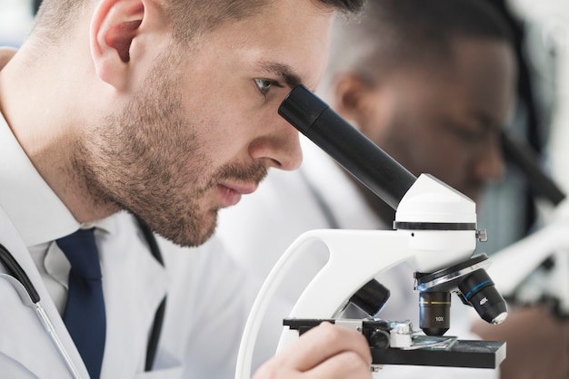 Foto knappe dokter die microscoop bekijkt