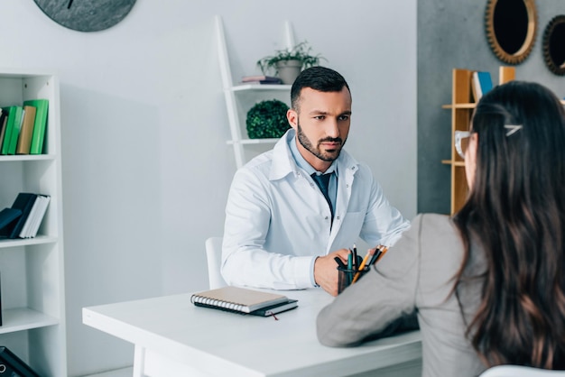 Knappe dokter in gesprek met patiënt in kliniek