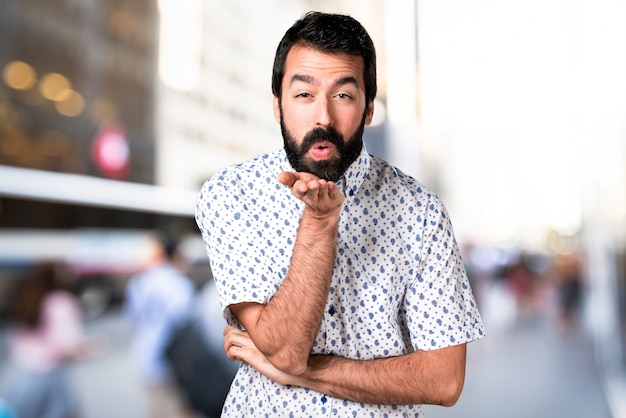 Knappe donkerbruine mens die met baard een kus verzendt