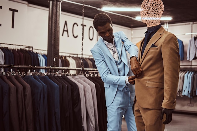 Knappe elegant geklede Afro-Amerikaanse man aan het werk bij klassieke herenkleding winkel.