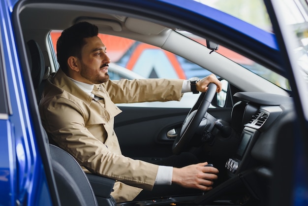 Knappe elegante ernstige man bestuurt een auto