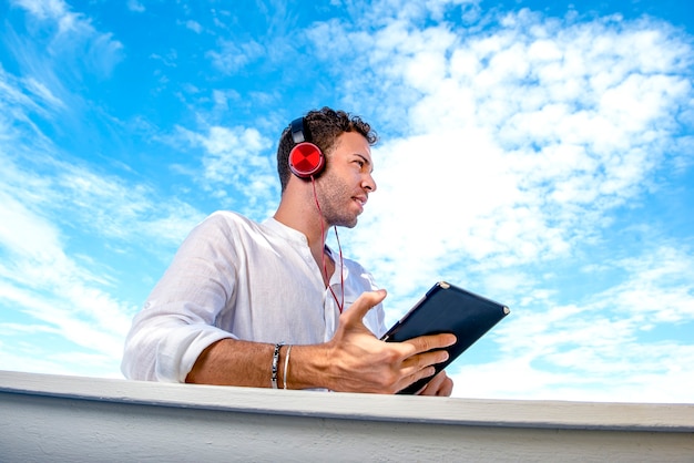 Knappe en succesvolle blanke man luisteren muziek op het strand. freelance en op afstand werken. student aan de Middellandse Zee