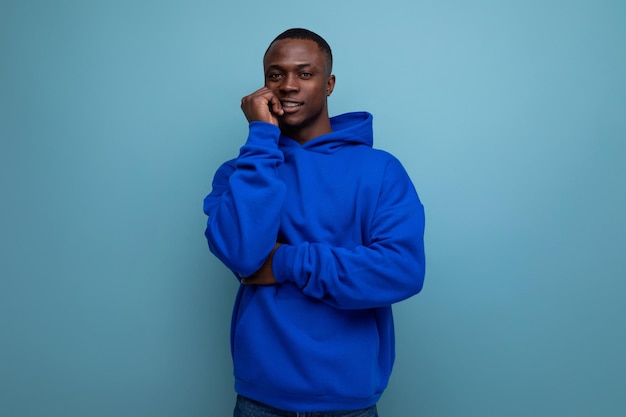 Knappe etnische jonge Afrikaanse man in stijlvolle hoodie op studio achtergrond met kopieerruimte