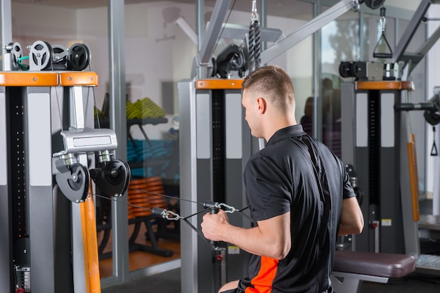 Knappe fit man training op rij machine in de fitnessruimte in het fitnesscentrum