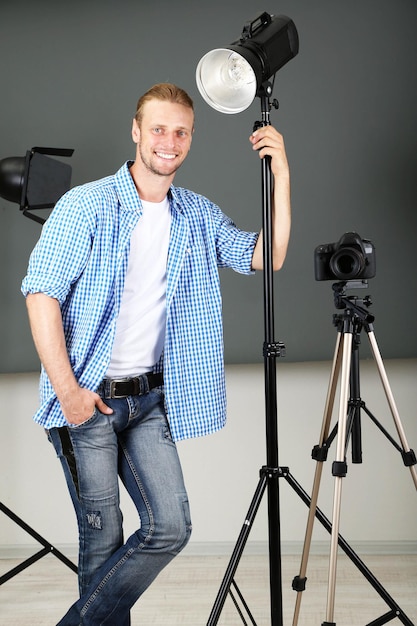 Knappe fotograaf met camera bij het werken aan de achtergrond van de fotostudio