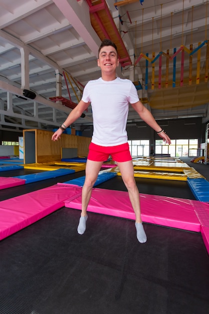 Knappe gelukkig man springen op een trampoline binnenshuis.