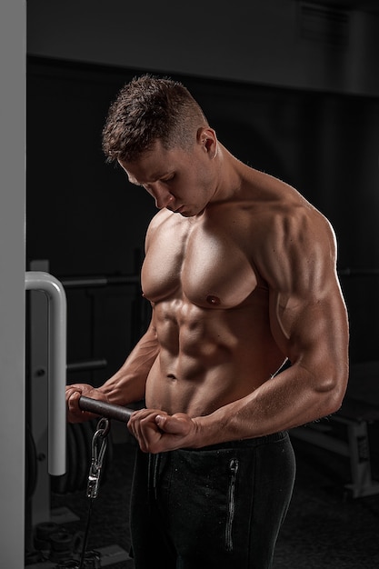 Foto knappe gespierde fitness bodybuilder doet zware oefening voor biceps op machine met kabel