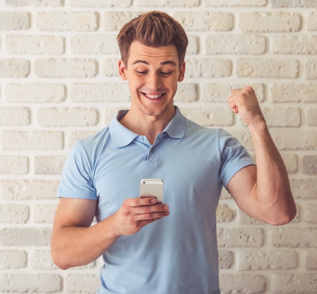 Knappe gespierde man in blauw t-shirt gebruikt smartphone