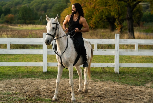 Knappe gespierde man rijdt paard Hunky cowboy Jonge gespierde man in tshirt te paard