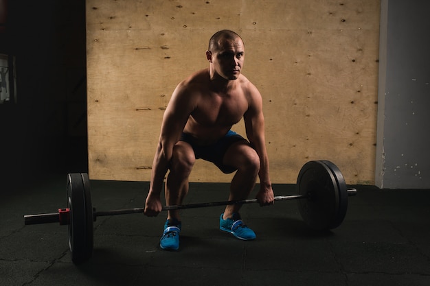 Knappe gewichtheffer die voor opleiding met barbell voorbereidingen treft