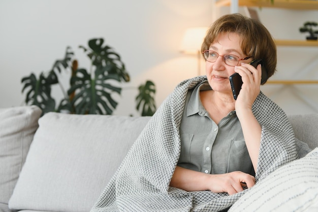 Knappe grootmoeder die thuis aan de telefoon praat