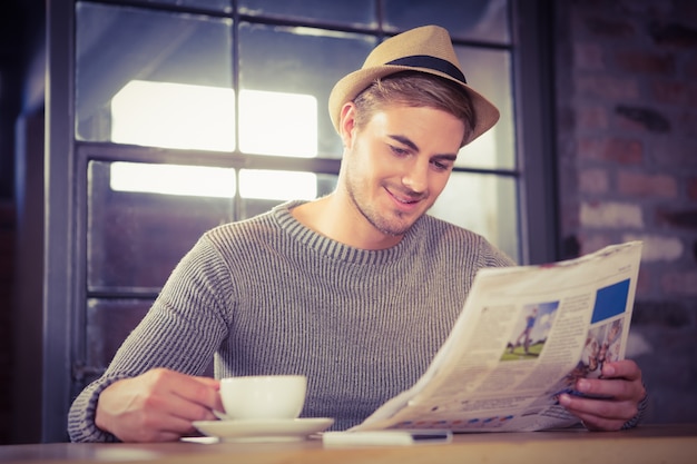 Foto knappe hipster die koffie heeft en krant leest