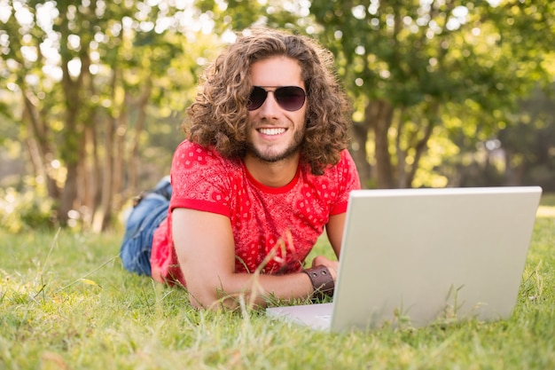 Knappe hipster die laptop in het park met behulp van