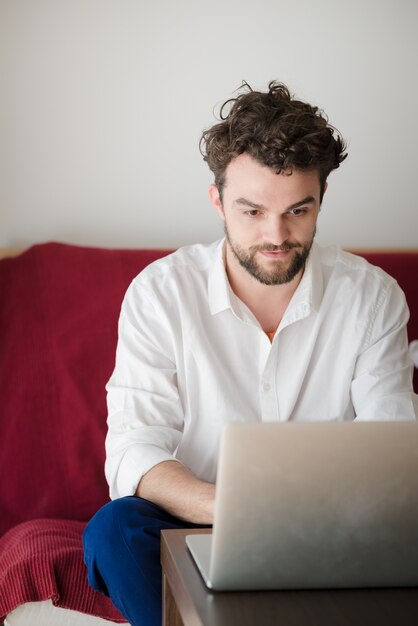 knappe hipster moderne man thuis werken met behulp van laptop