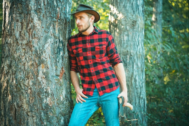 Knappe houtbewerkers houthakker plaid shirt met de bijl op groene natuur achtergrond ontbossing...