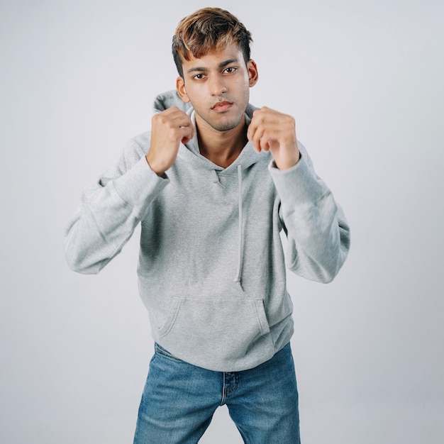 Foto knappe indiase jonge man hoodie vechten houding geïsoleerde grijze muur