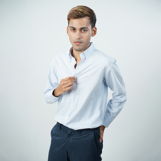 Foto knappe indiase jonge zakenman die shirt geïsoleerde grijze muur repareert