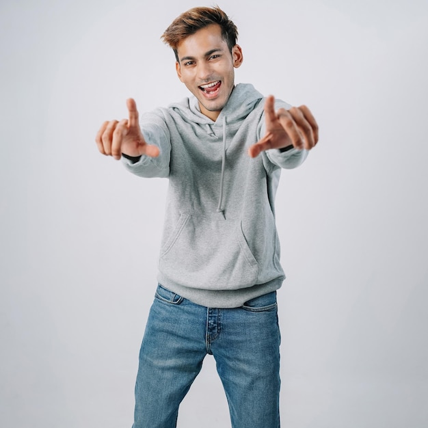 Foto knappe indiase jongeman hoodie wijzend glimlachend geïsoleerde grijze muur