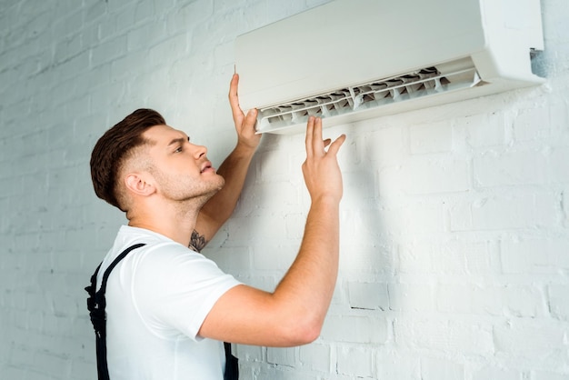 Knappe installateur die naar airconditioner kijkt