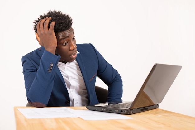 knappe jonge Afrikaanse man aan tafel met laptop met verbaasd gezicht