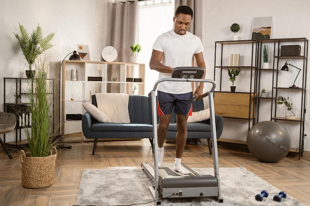 Knappe jonge Afrikaanse sportman traint op de achtergrond van een helder modern appartement