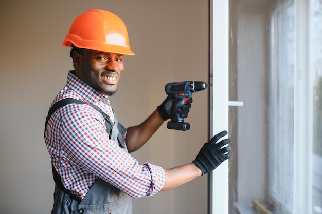 knappe jonge Afro-Amerikaanse man die bay window installeert op de bouwplaats van een nieuw huis