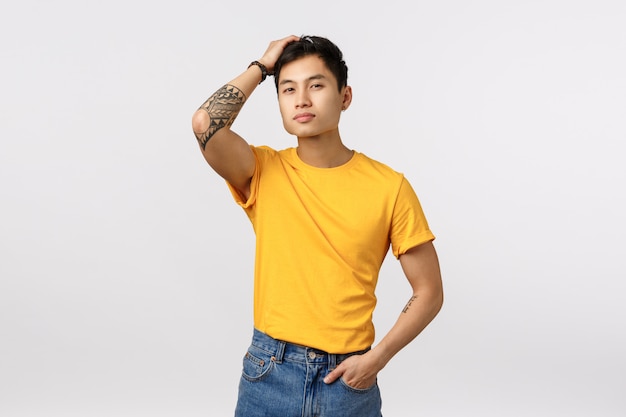 Knappe jonge Aziatische man in gele t-shirt poseren